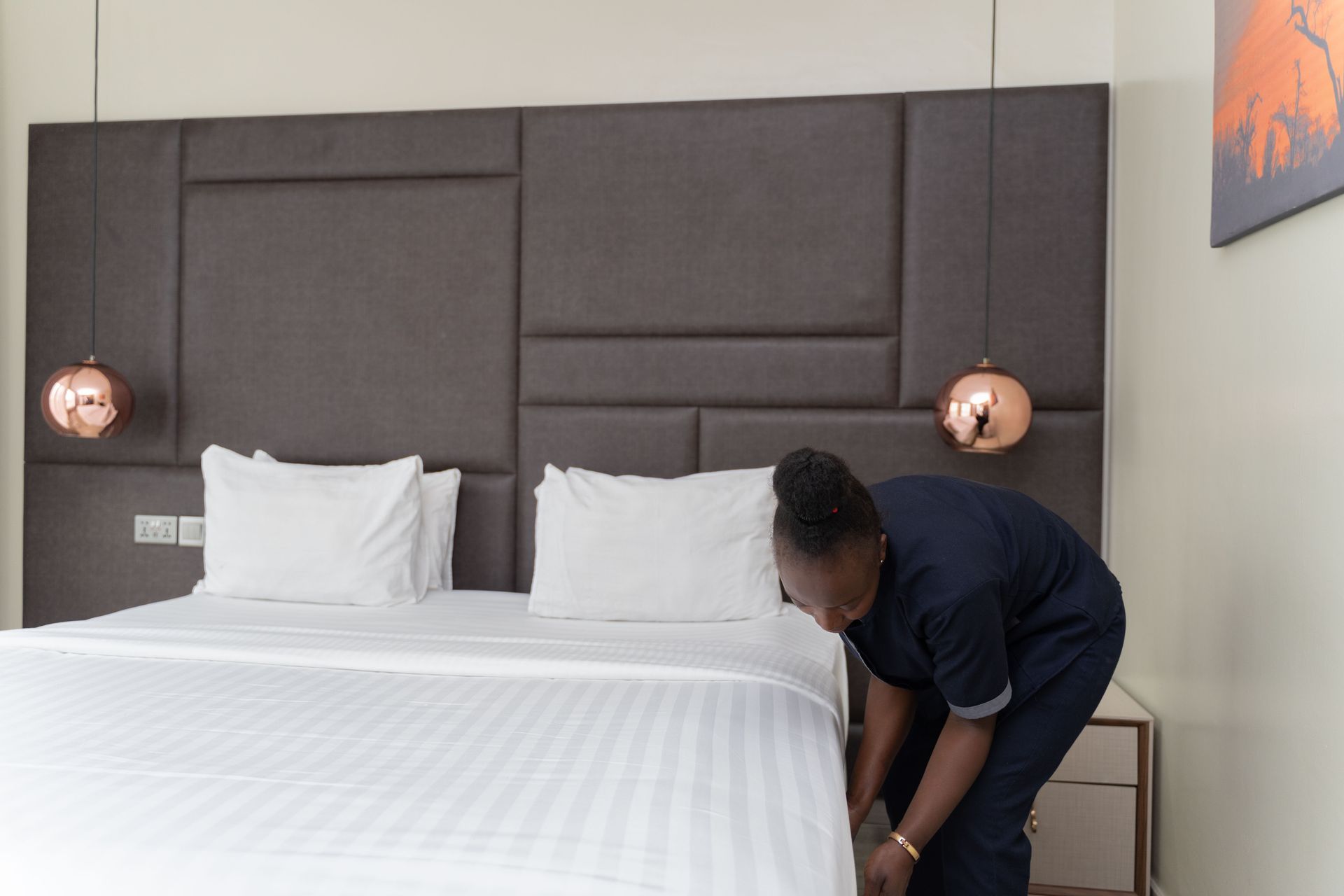 Hotelmitarbeiter macht ein Bett in einem modernen Hotelzimmer