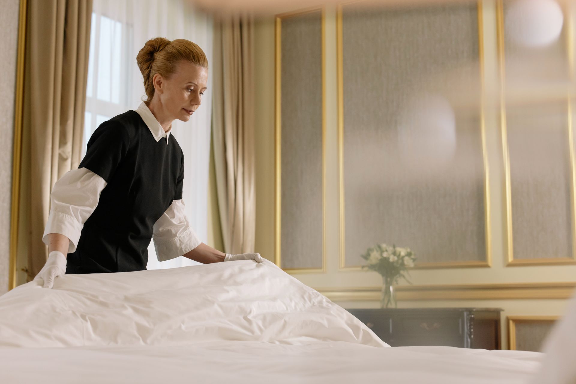 Mitarbeiterin richtet das Bett in einem Hotelzimmer